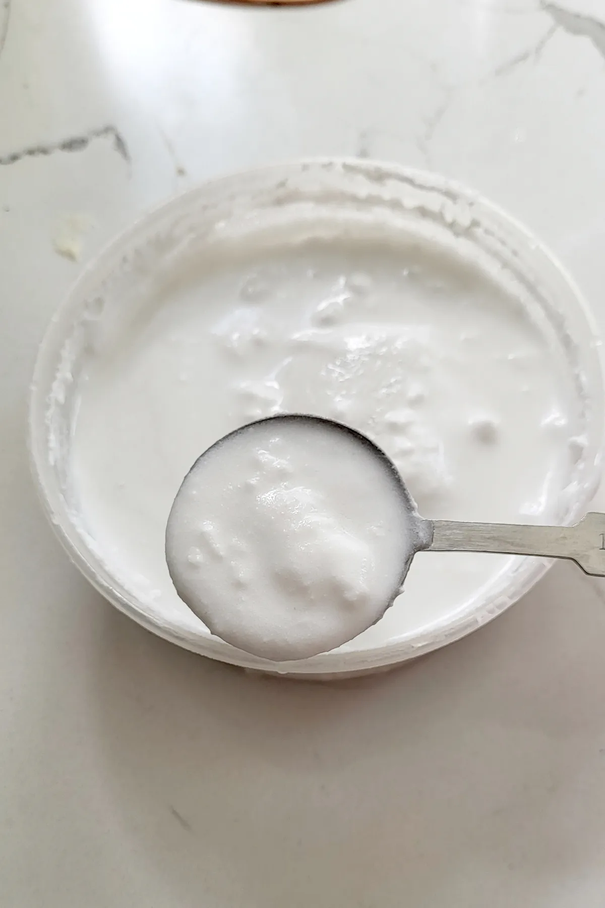 a spoonful of coconut cream skimmed from a bowl of coconut milk.