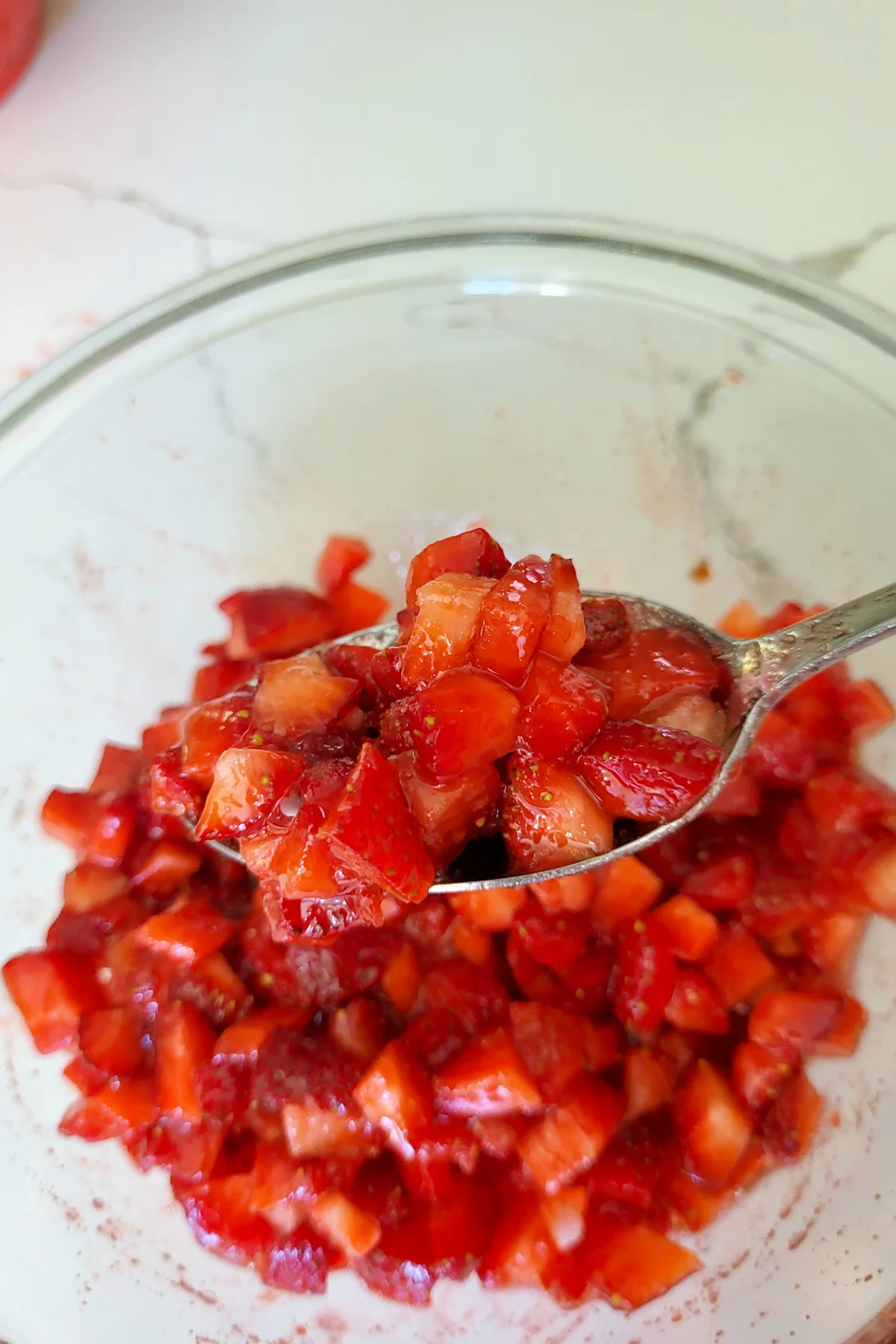 a bowl of diced strawberries with juice.
