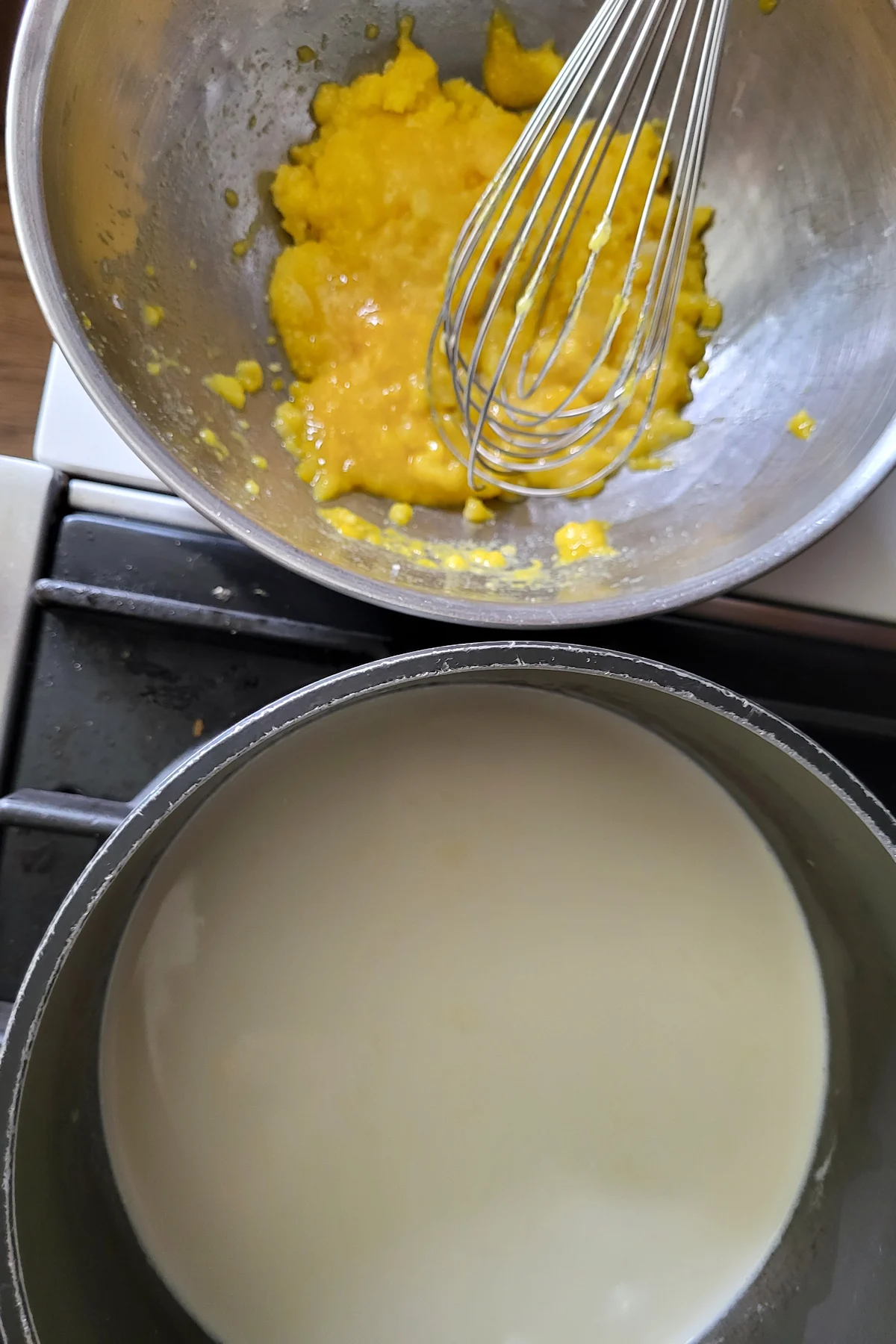 a bowl of egg yolks and a pot of heavy cream.