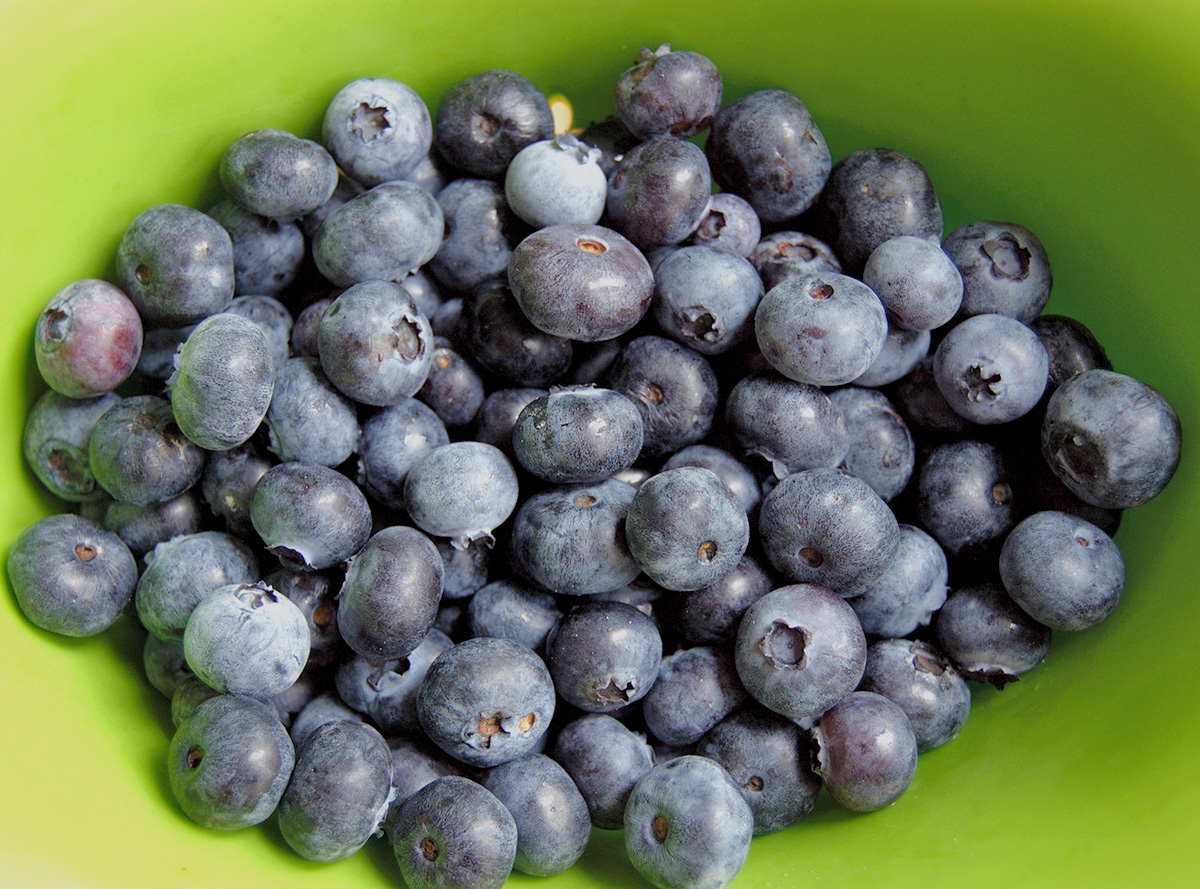 a green bowl full of blueberries.