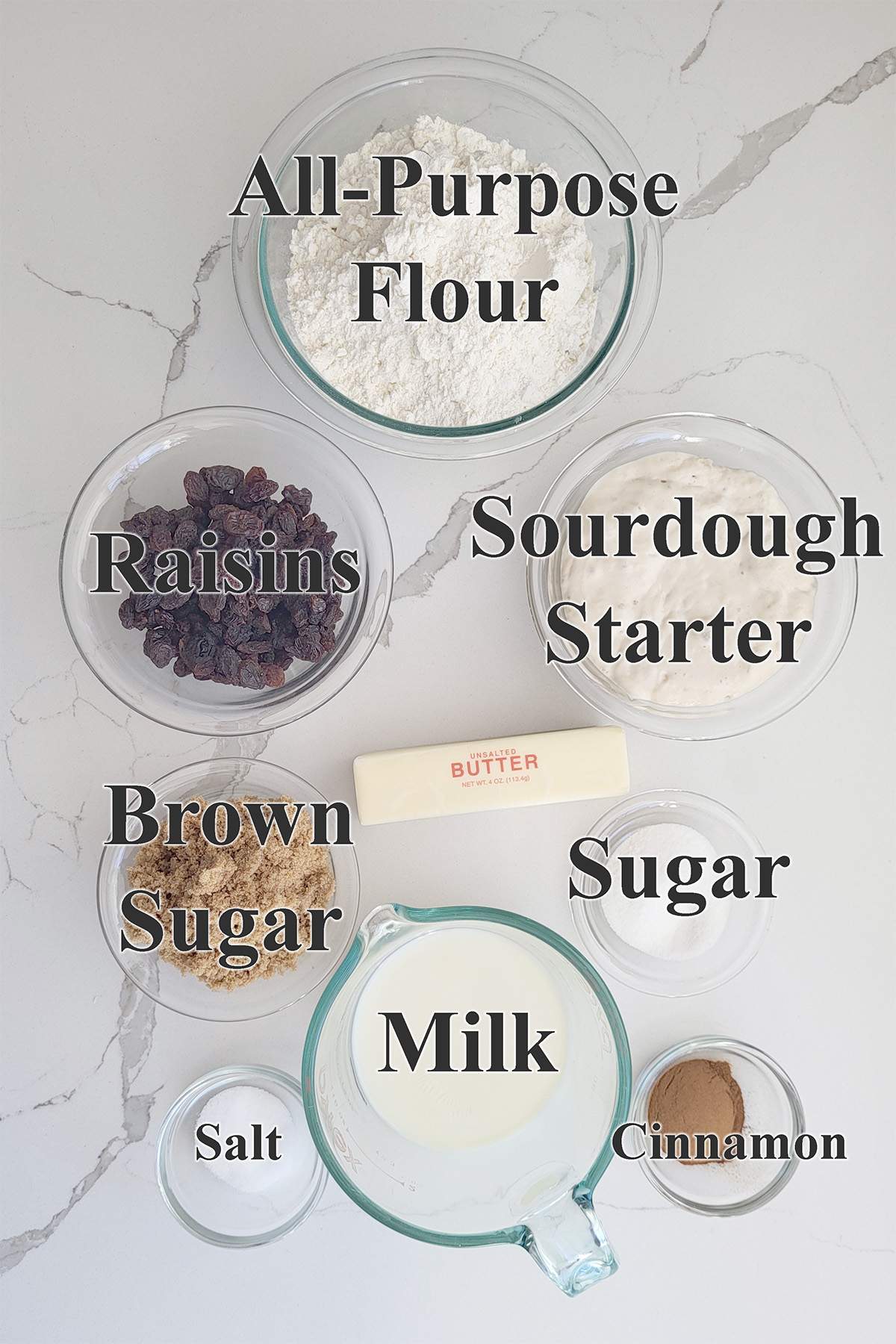 ingredients for sourdough cinnamon raisin bread in glass bowls.