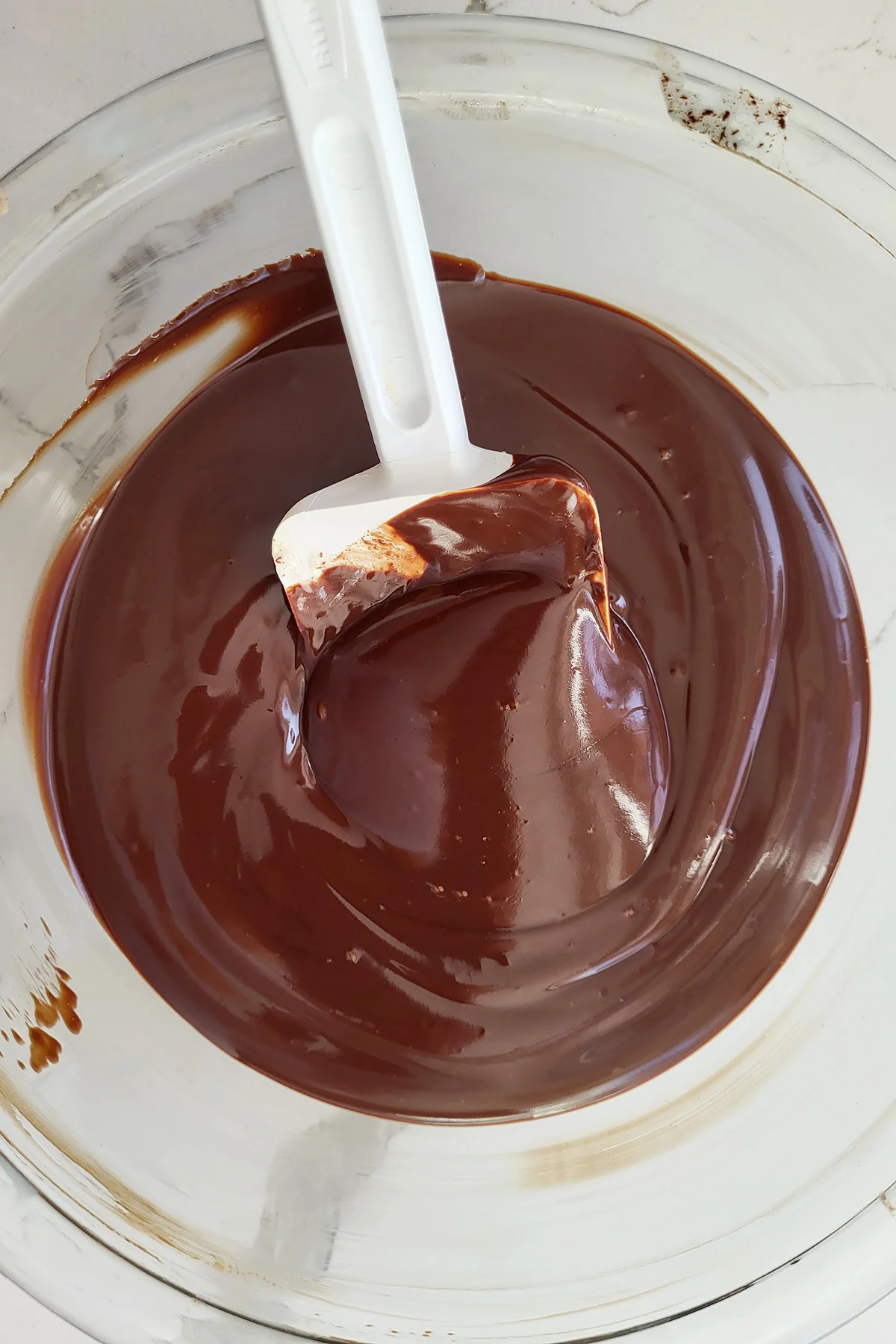 a bowl of chocolate ganache with a spatula.