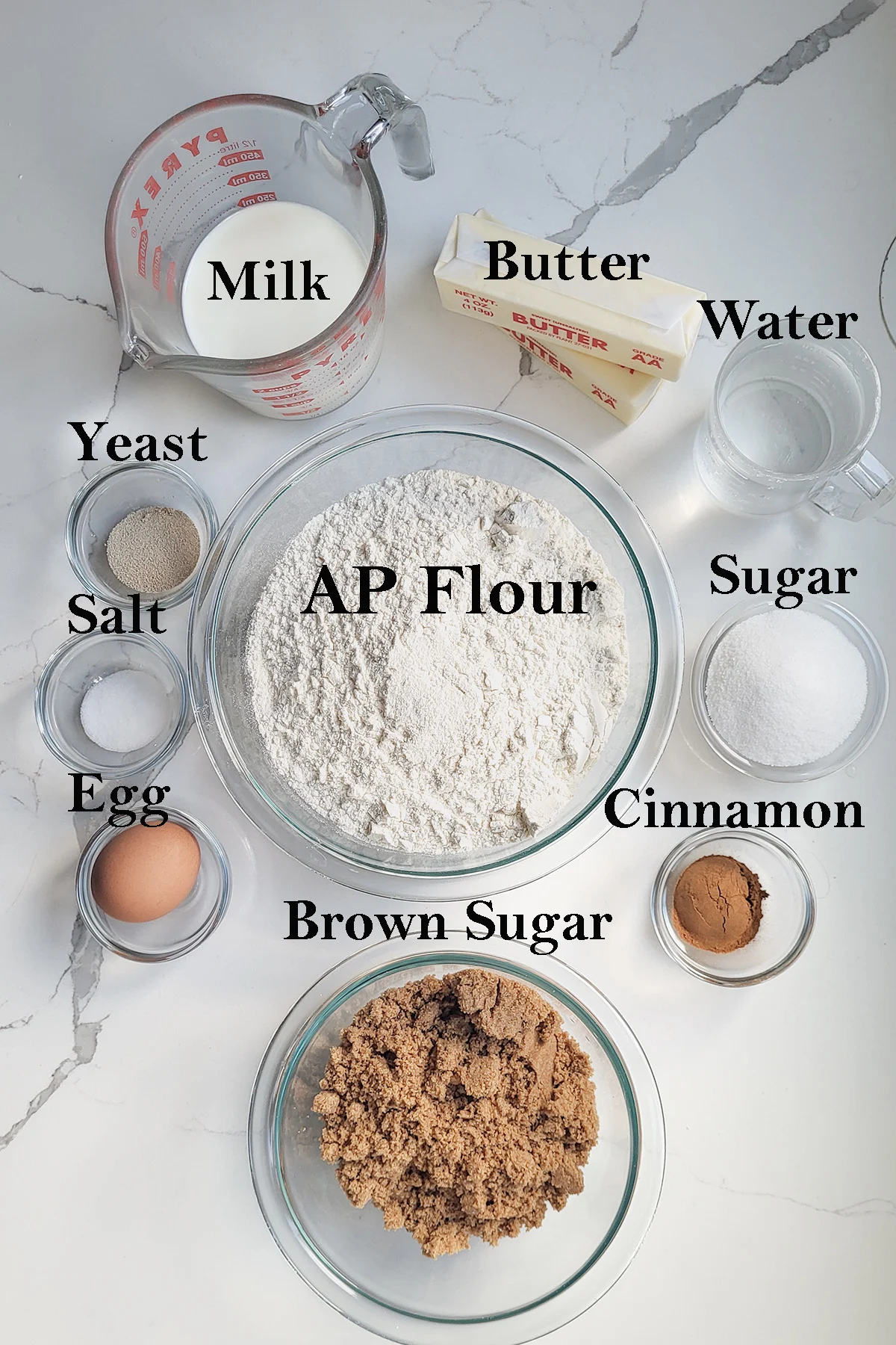 ingredients for cinnamon buns displayed in bowls with text overlay