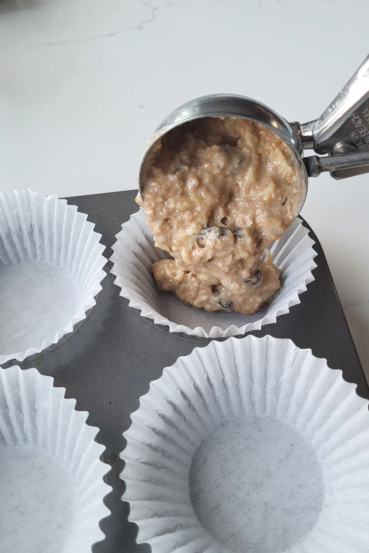 A scoop of bran muffin batter in a muffin pan.