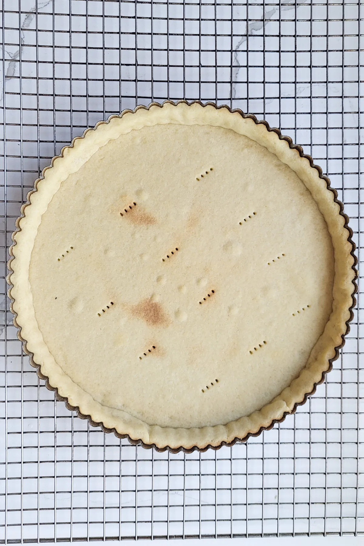 a prebaked tart shell on a cooling rack.