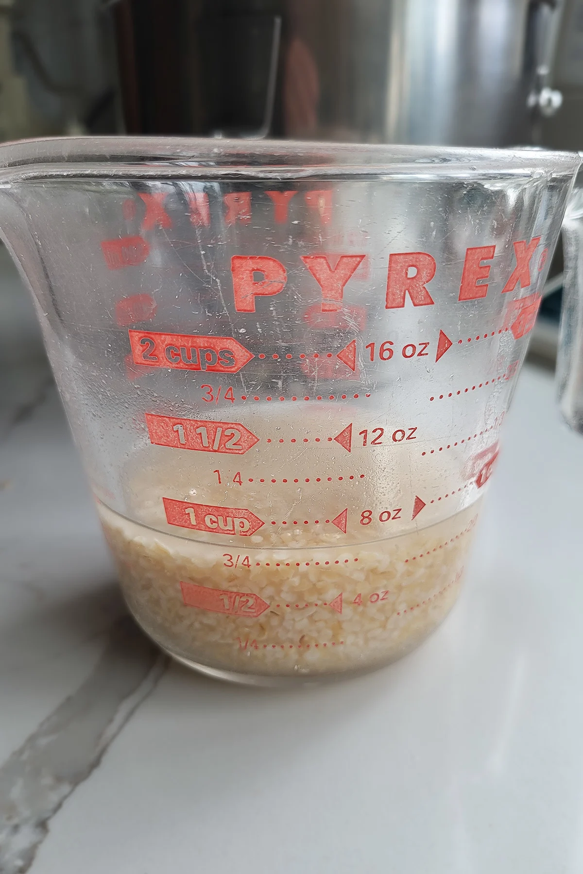 a glass measuring cup filled with water and bulgur wheat.