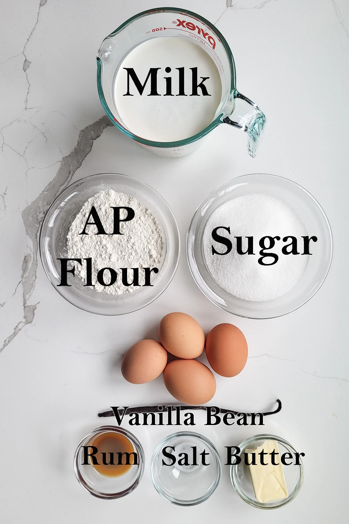 ingredients for caneles in glass bowls on a white surface.