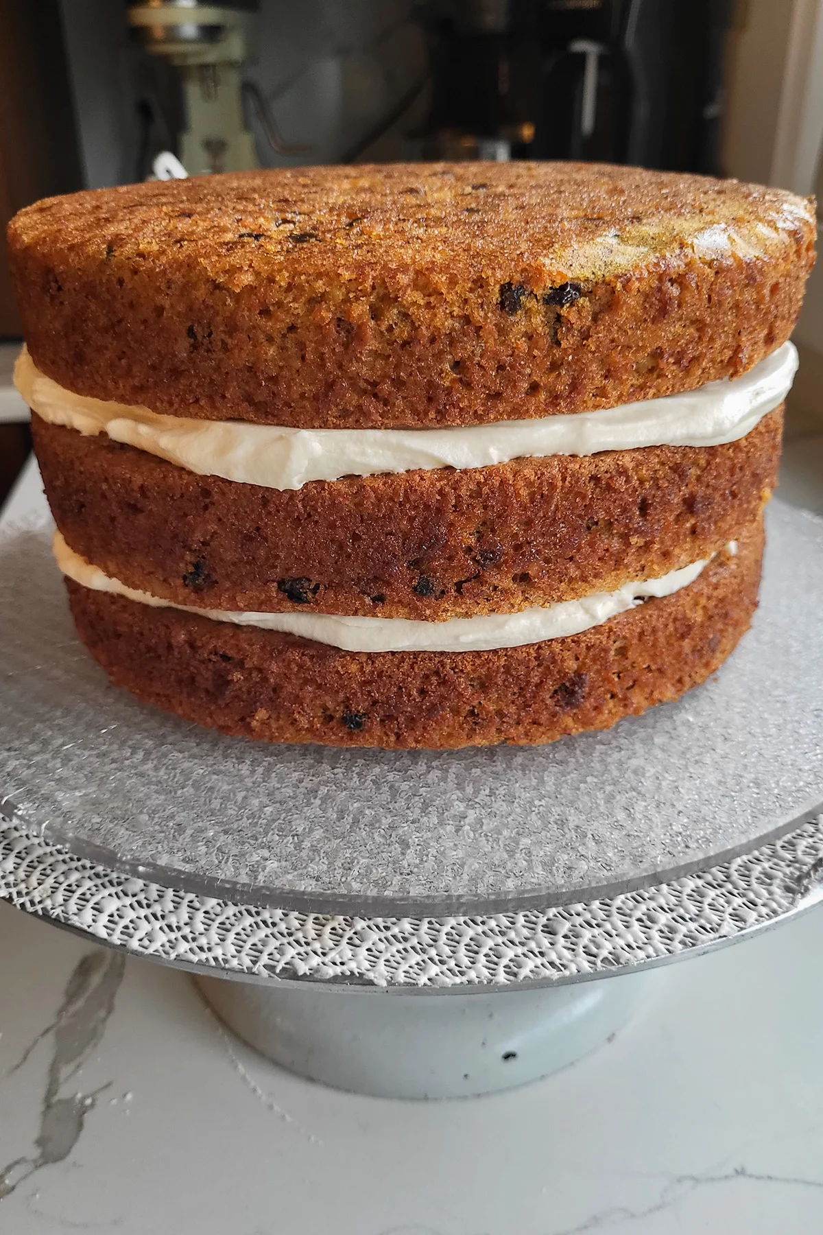 an uniced 3 layer carrot cake on a plate.