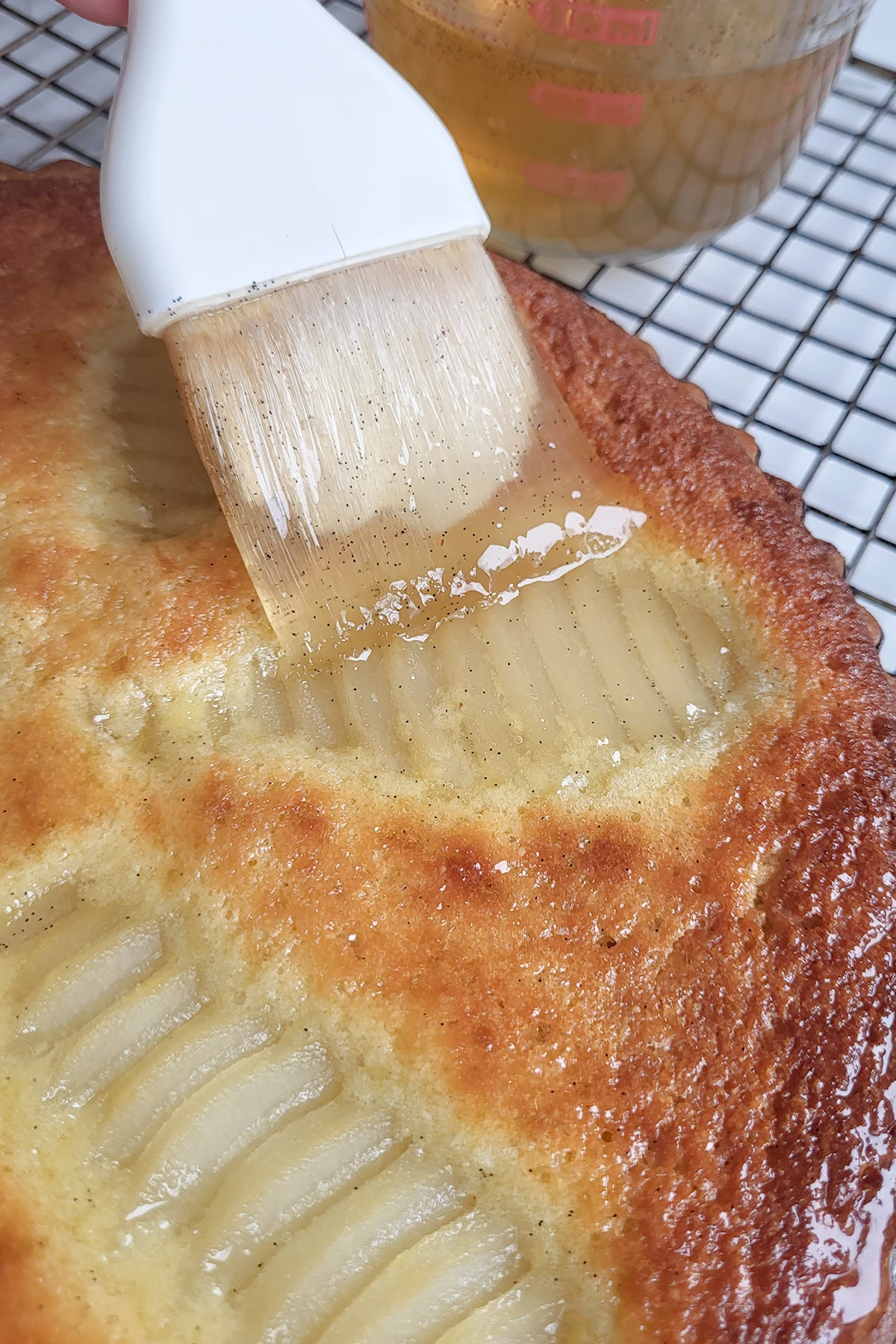 A pastry brush brushing syrup on a tart.