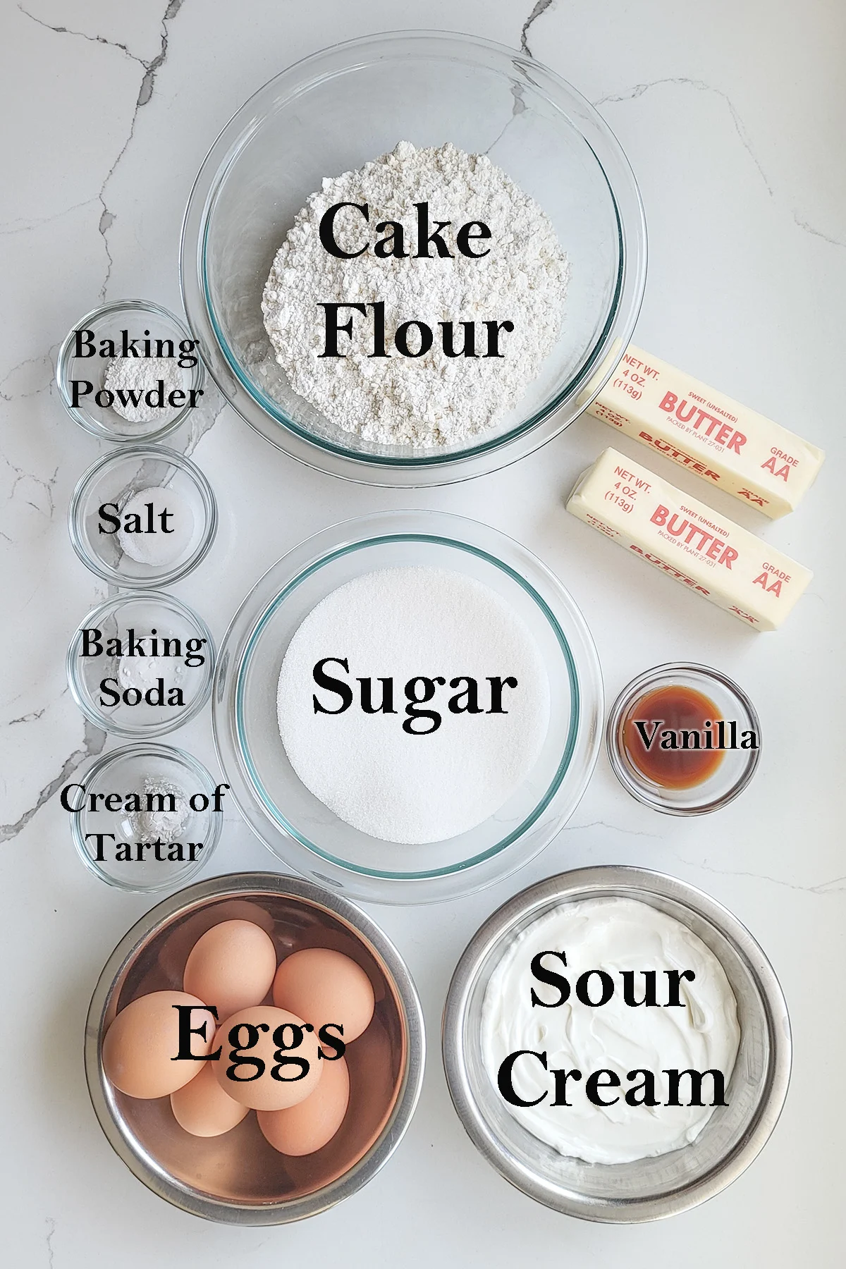 Vanilla cake ingredients in bowls with text overlay on the photo identifying the ingredients.