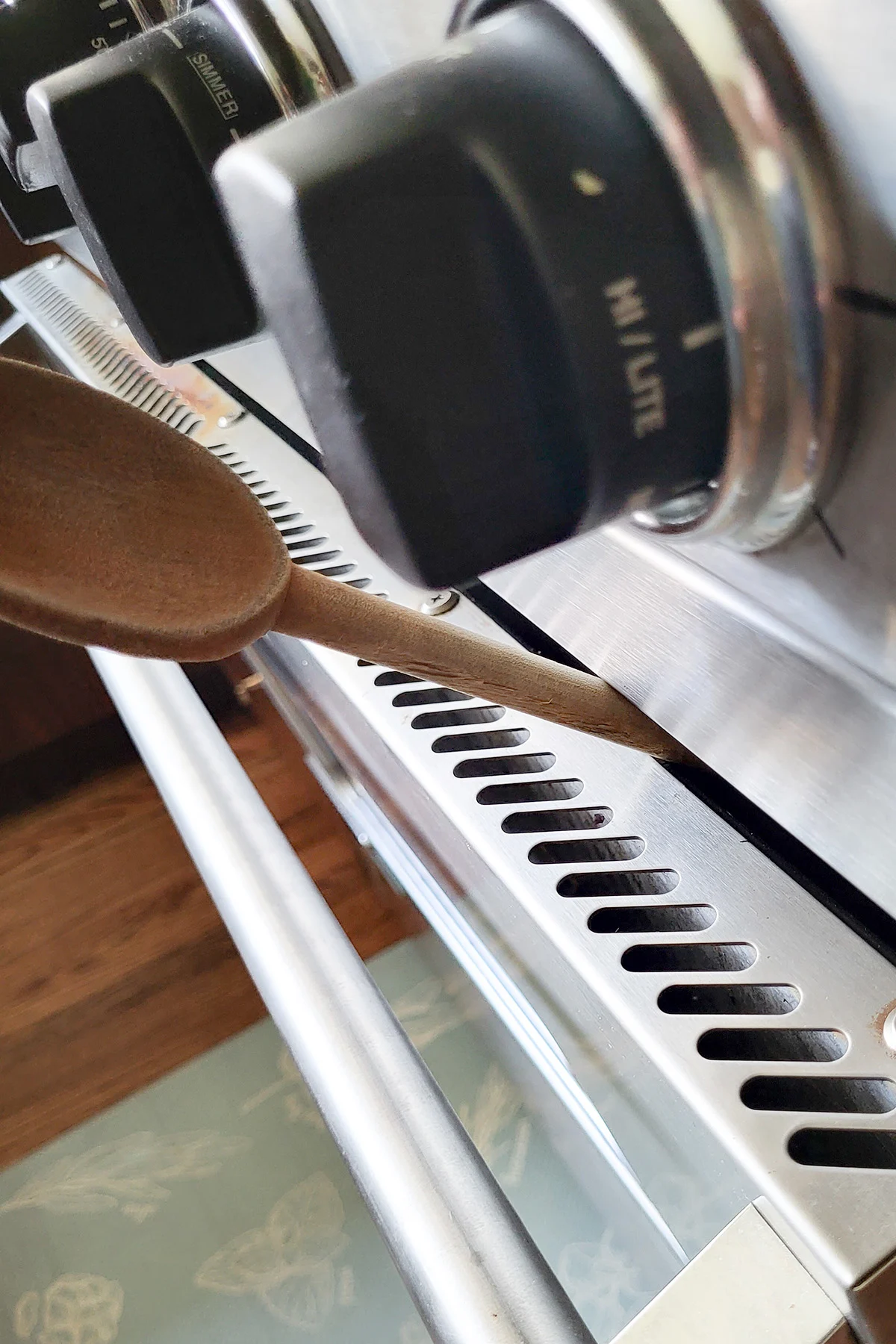 an oven door propped open with a spoon handle.