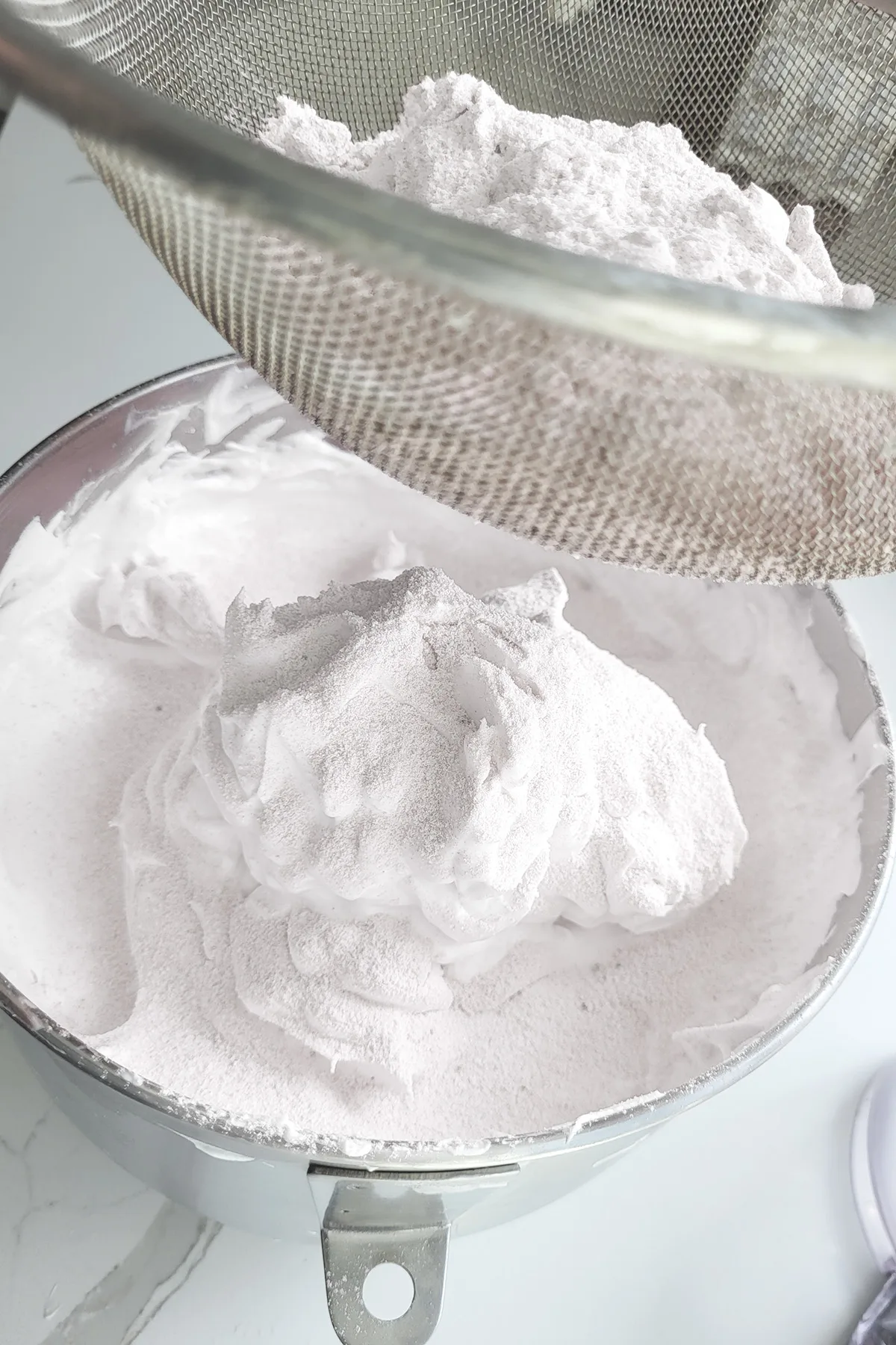 sifting flour into a bowl of egg whites.