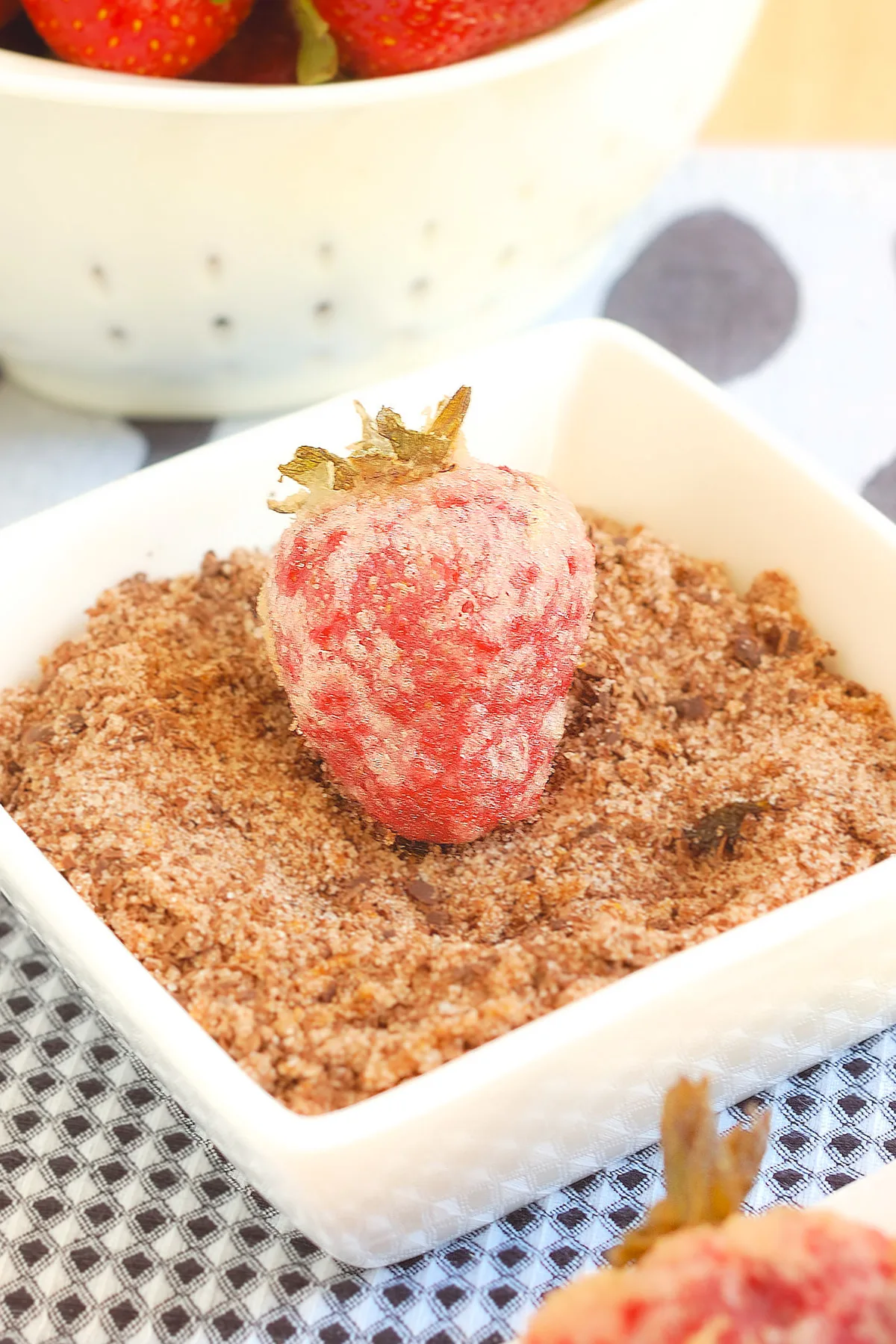 a tempura strawberry in a bowl of chocolate dipping sugar.