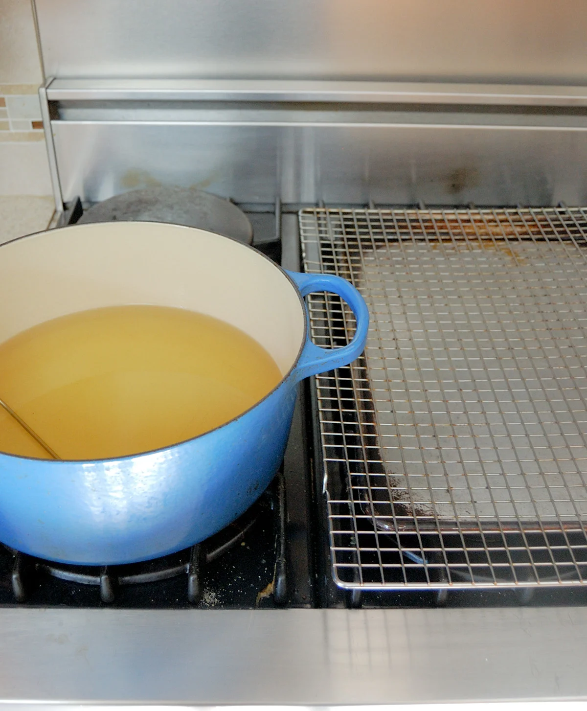 a pot of oil and a cooling rack over a sheet pan.