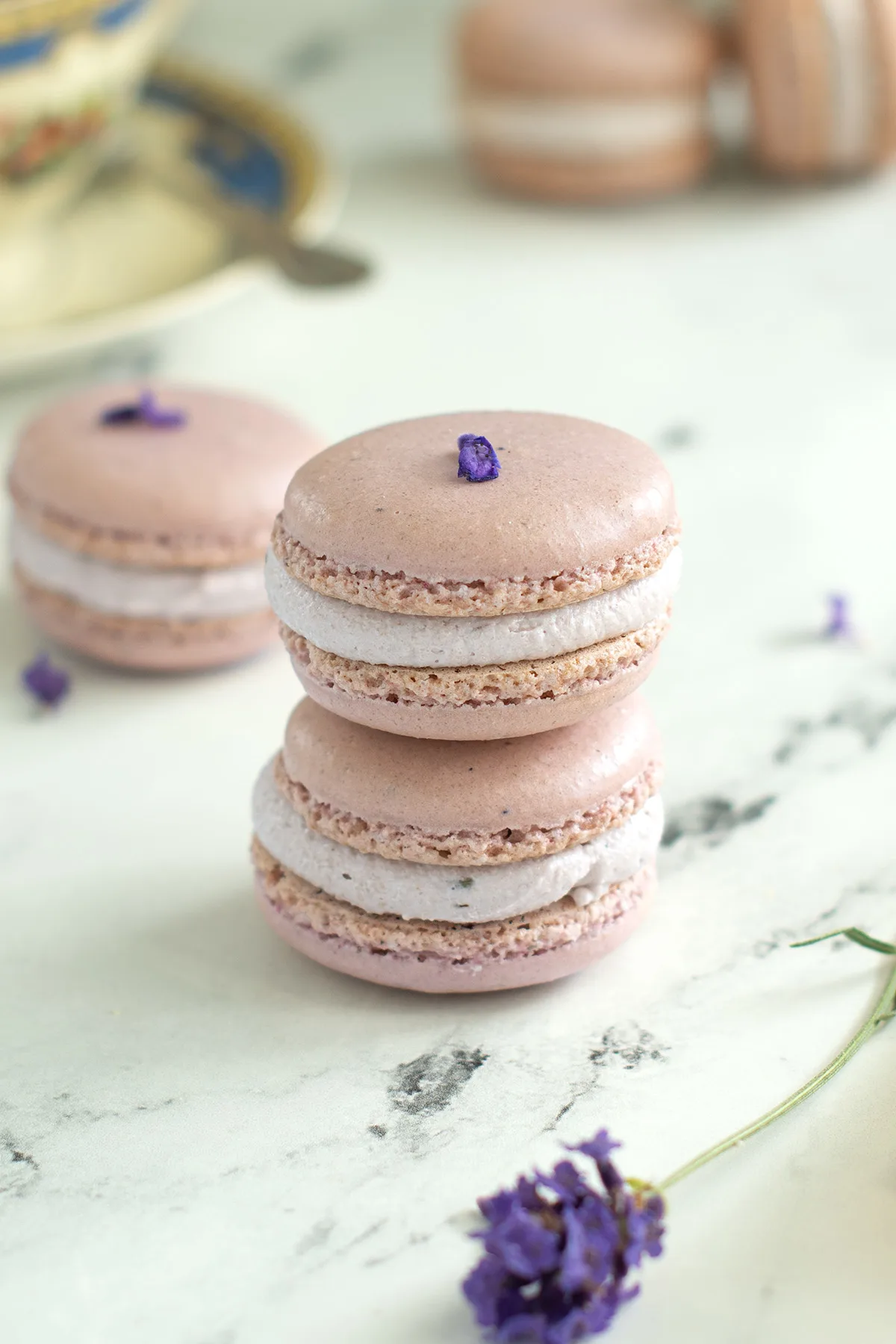 two lavender macarons on a marble surface.