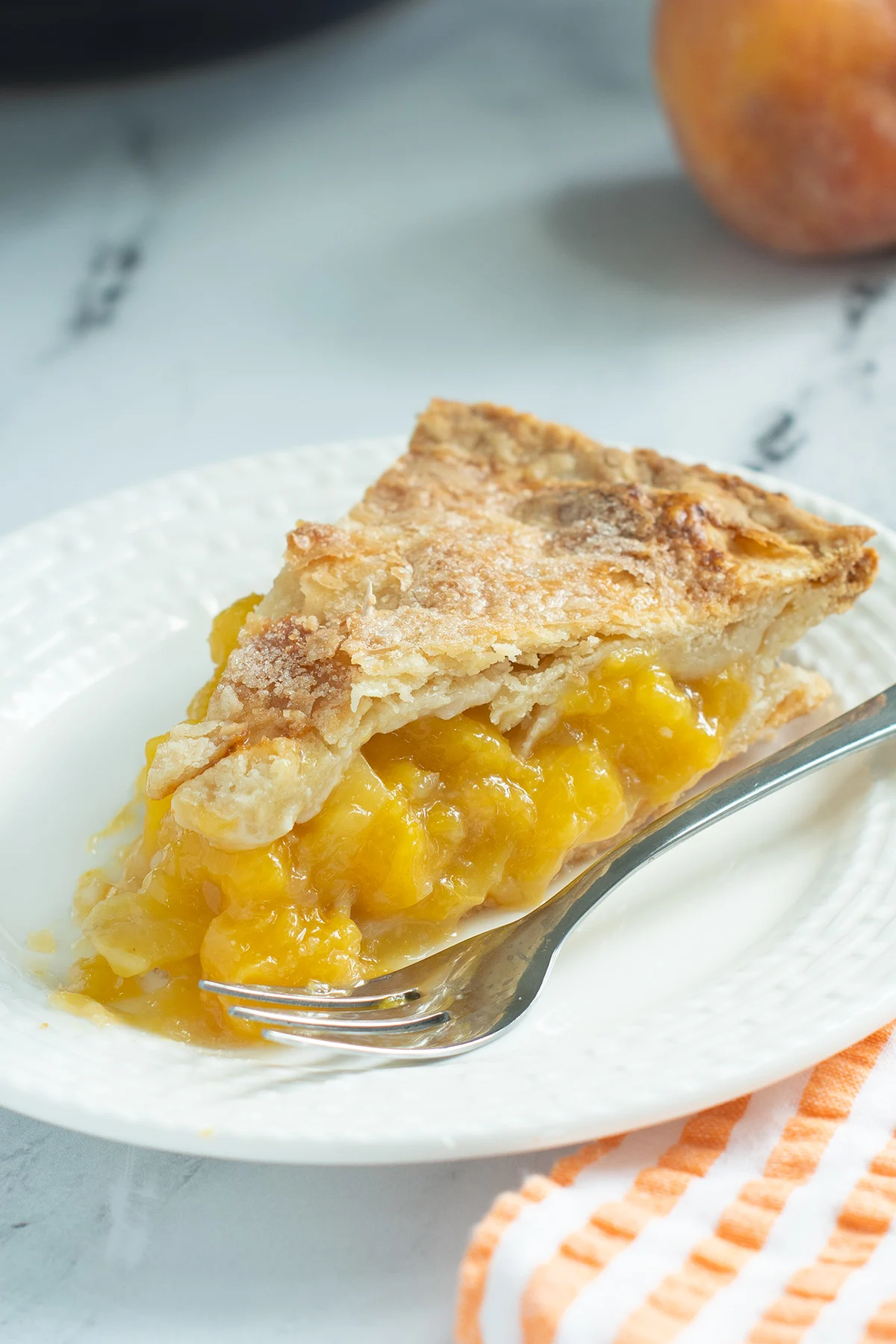 A slice of peach mango pie on a white plate.