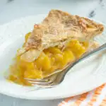 a slice of peach mango pie on a white plate.