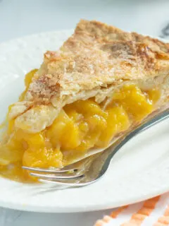 a slice of peach mango pie on a white plate.
