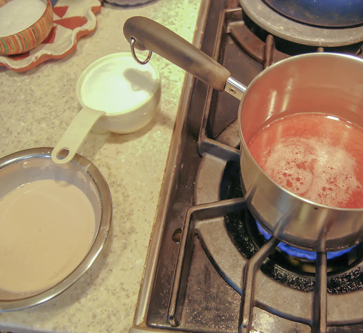 Cherry juice in pan on the stove. A bowl of cornstarch slurry.