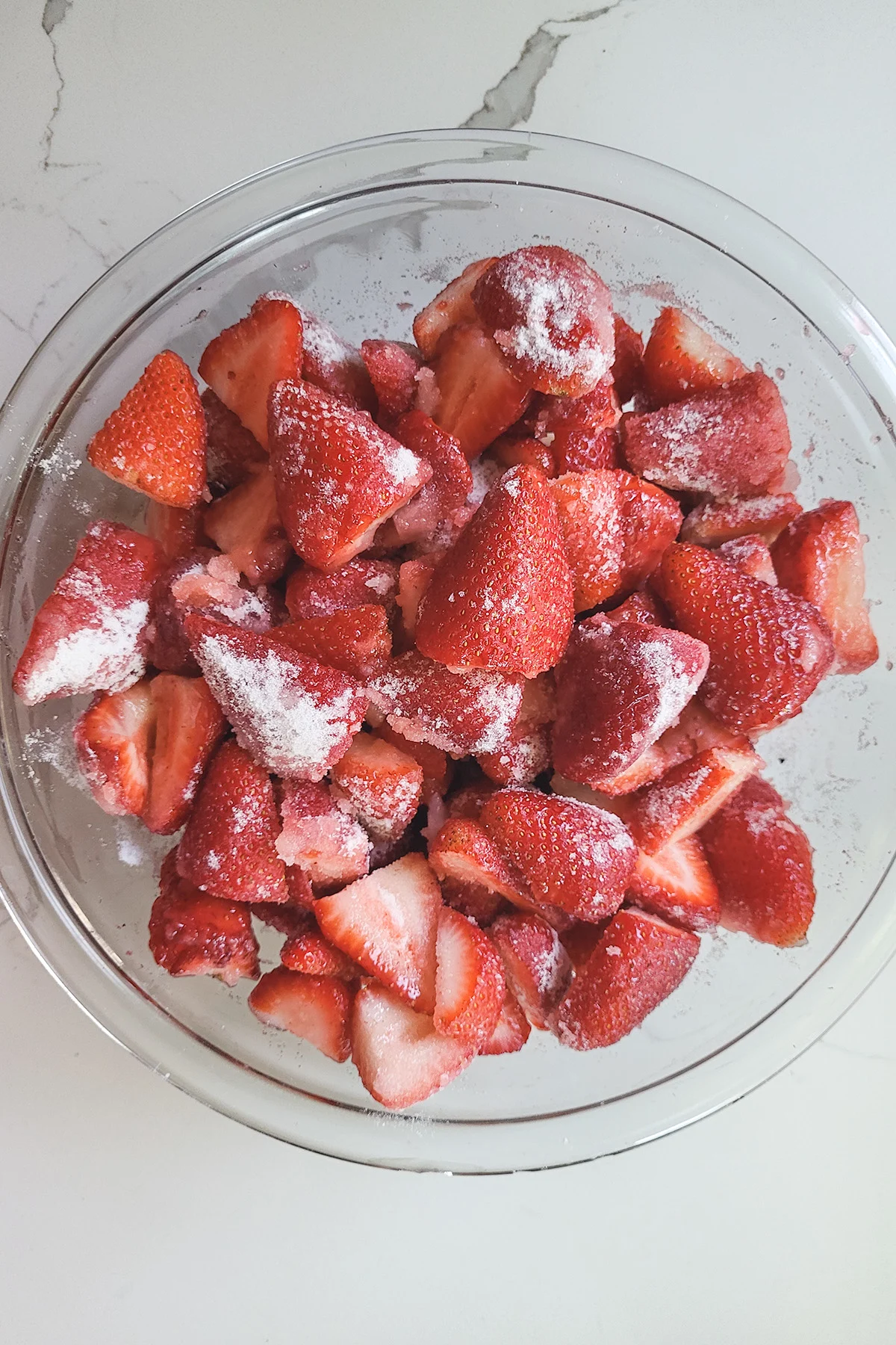 A bowl of strawberries with sugar.
