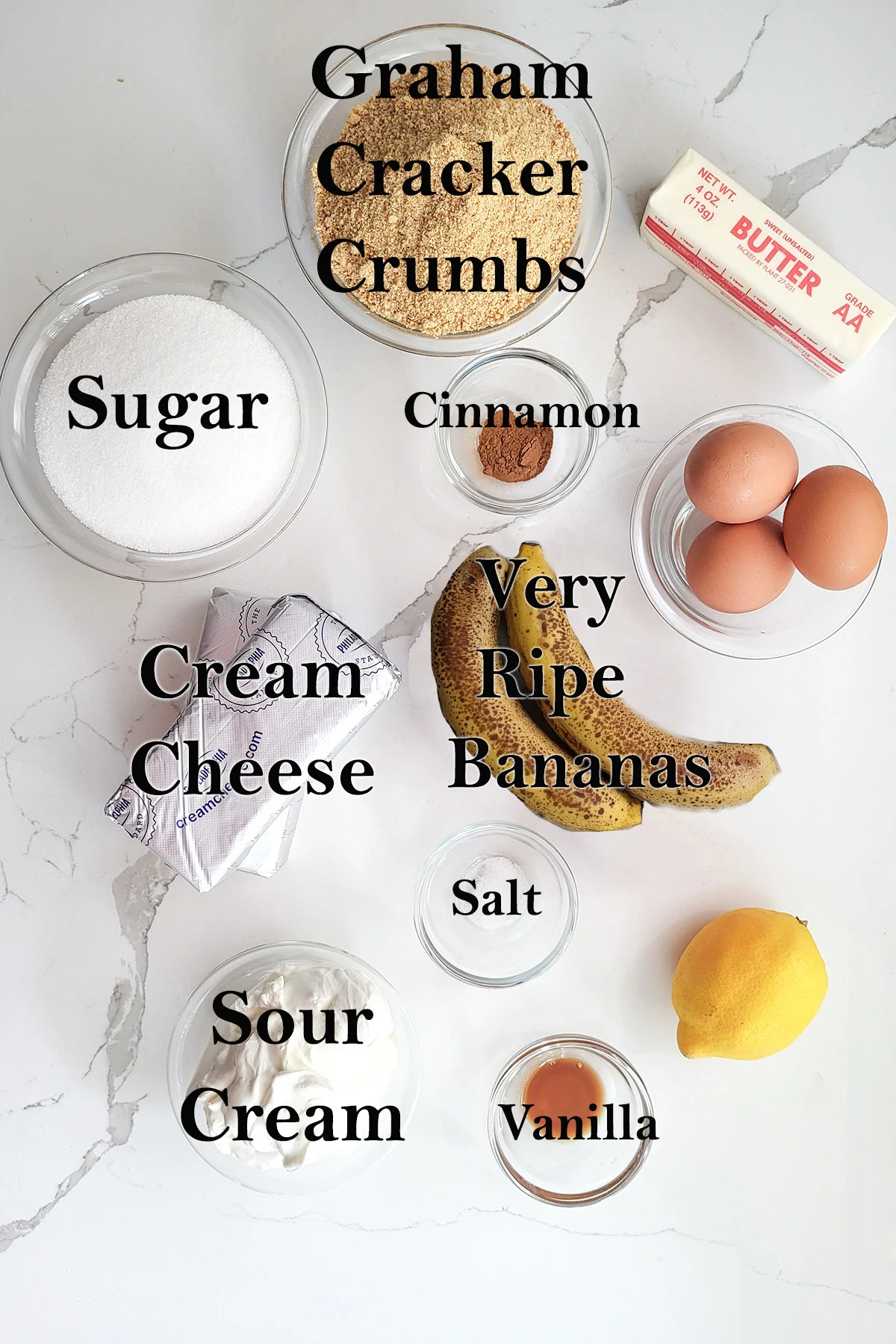 ingredients for banana cheesecake in glass bowls on a white surface.