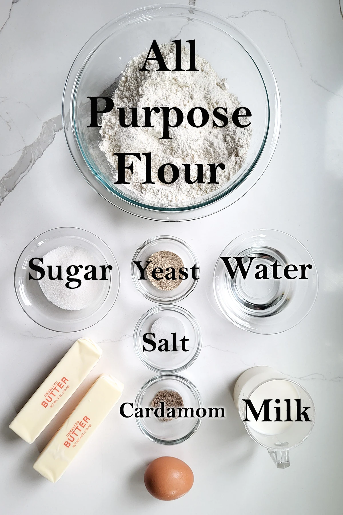 ingredients for danish dough in glass bowls on a white surface.