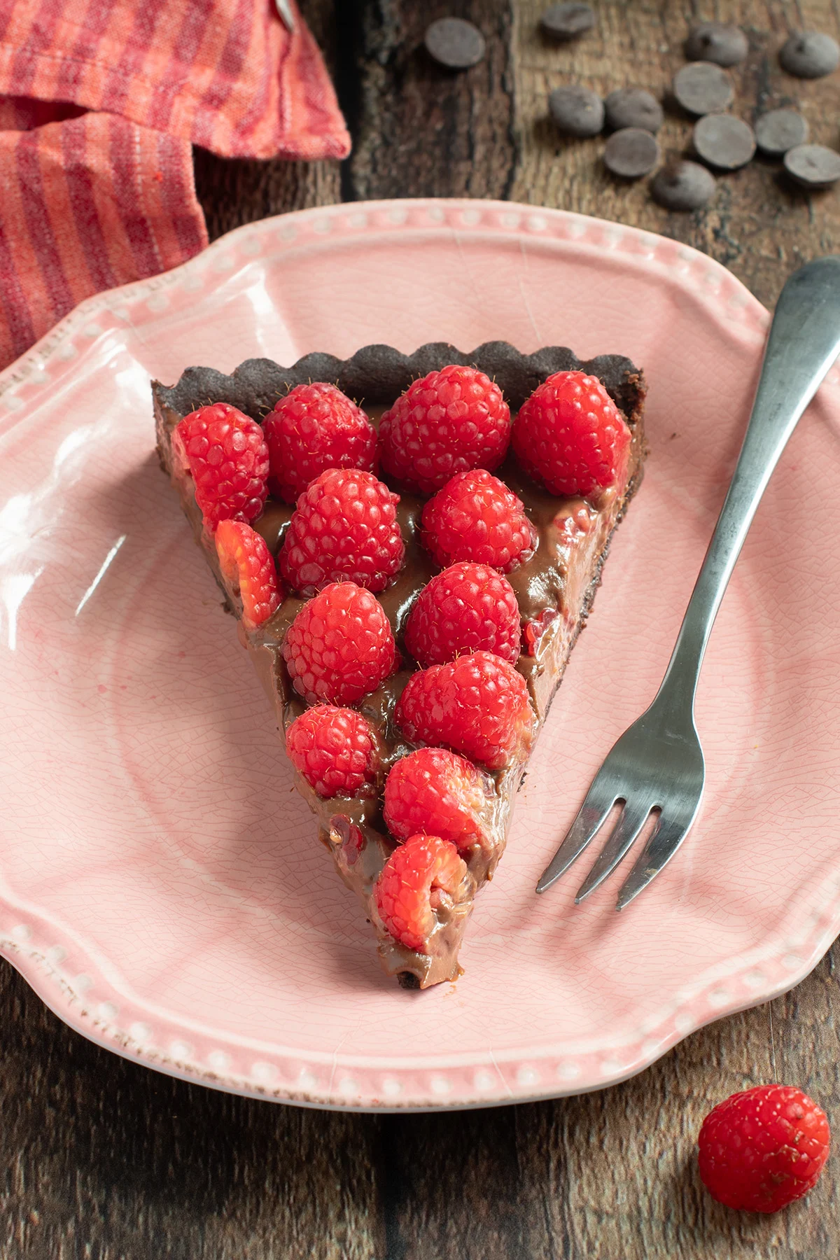 a slice of chocolate raspberry tart on a pink plate.