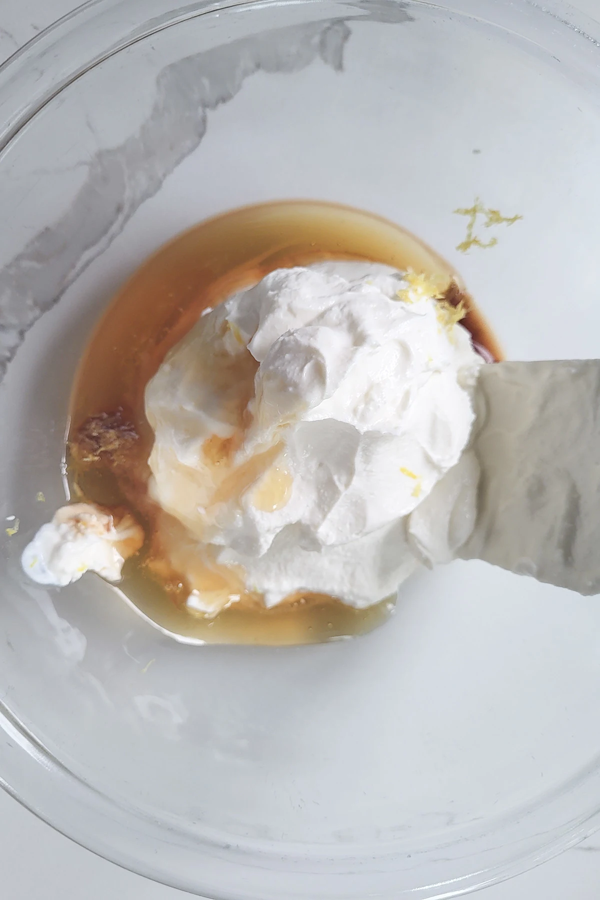 a glass bowl with ricotta cheese and honey being mixed together.