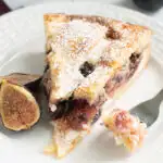 a slice of fig tart on a white plate with a fork.