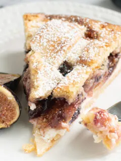 a slice of fig tart on a white plate with a fork.