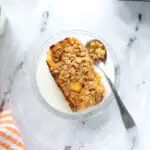 a slice of peach baked oatmeal on a glass plate with milk and a spoon.