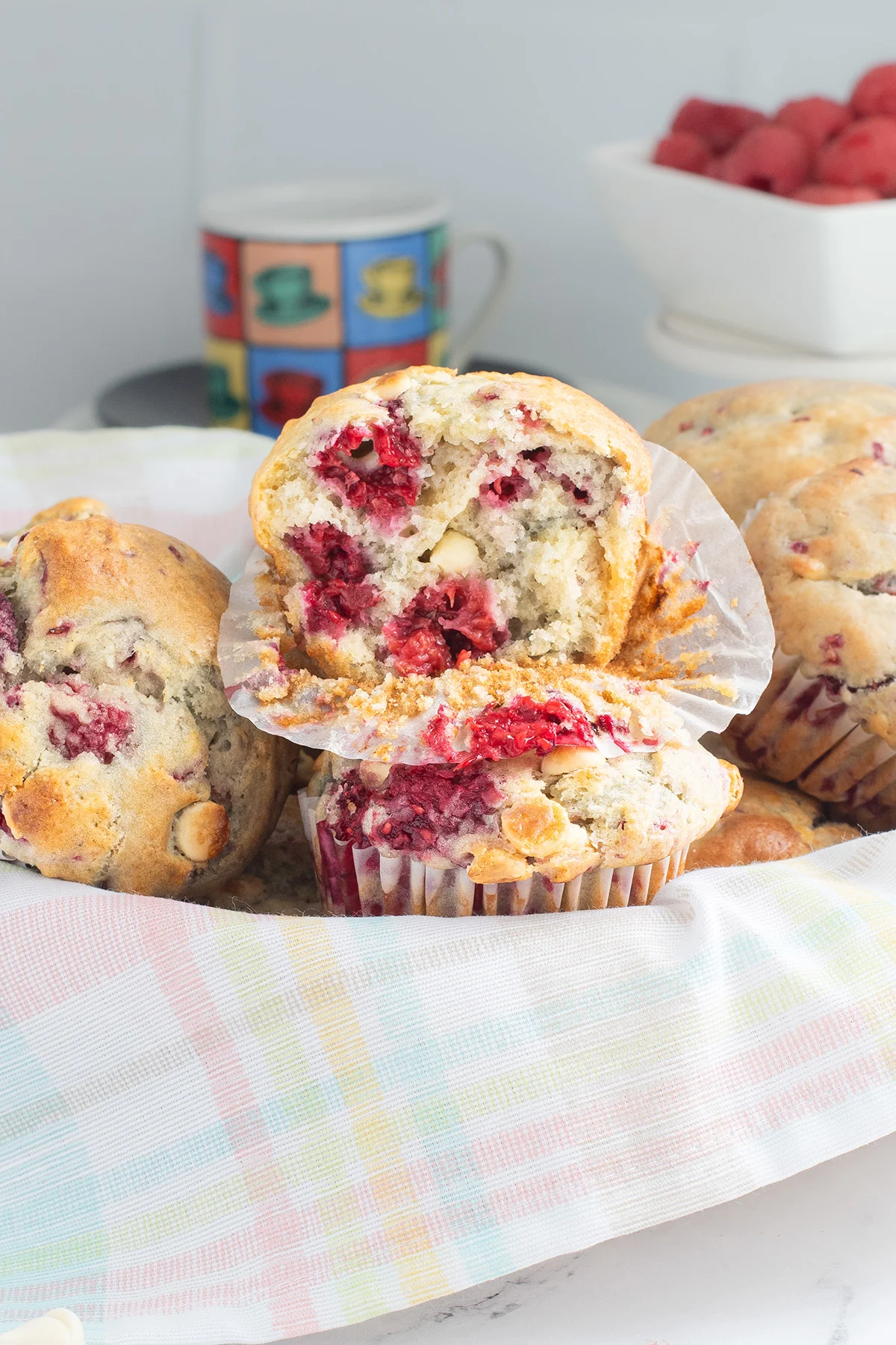 a basket of raspberry muffins with one cut in half.