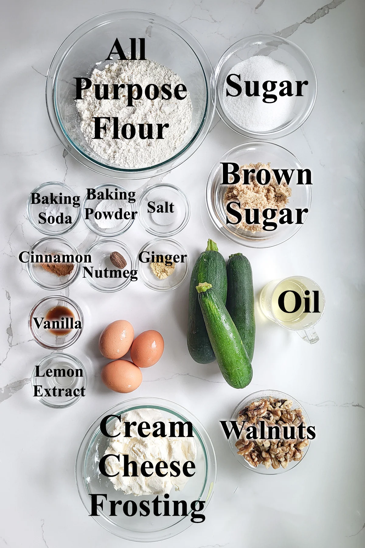 ingredients for zucchini cake in glass bowls on a white surface.