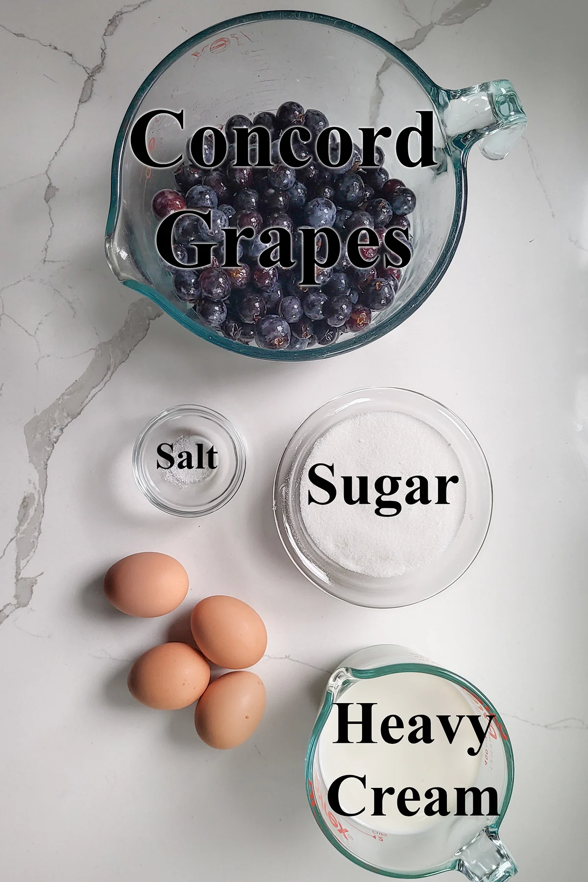 ingredients for concord grape ice cream in glass bowls on a white surface.