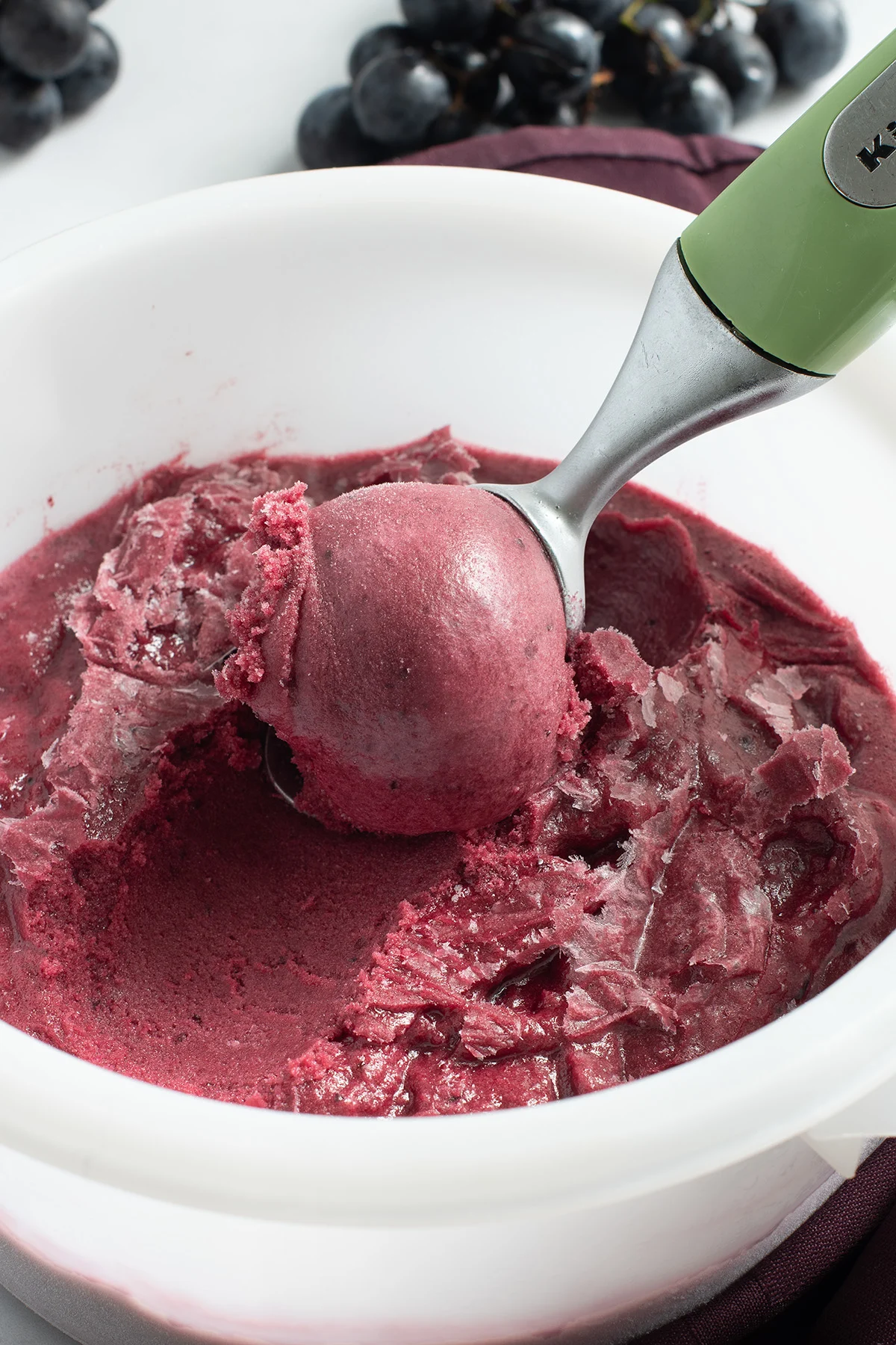 a container of concord grape sorbet with an ice cream scoop in it.
