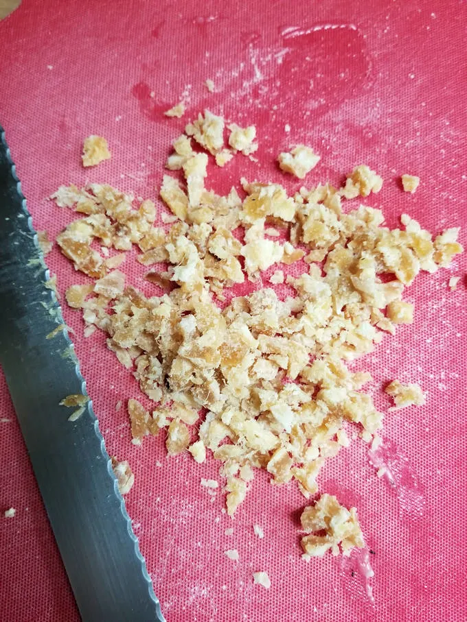 minced ginger on a red cutting board.