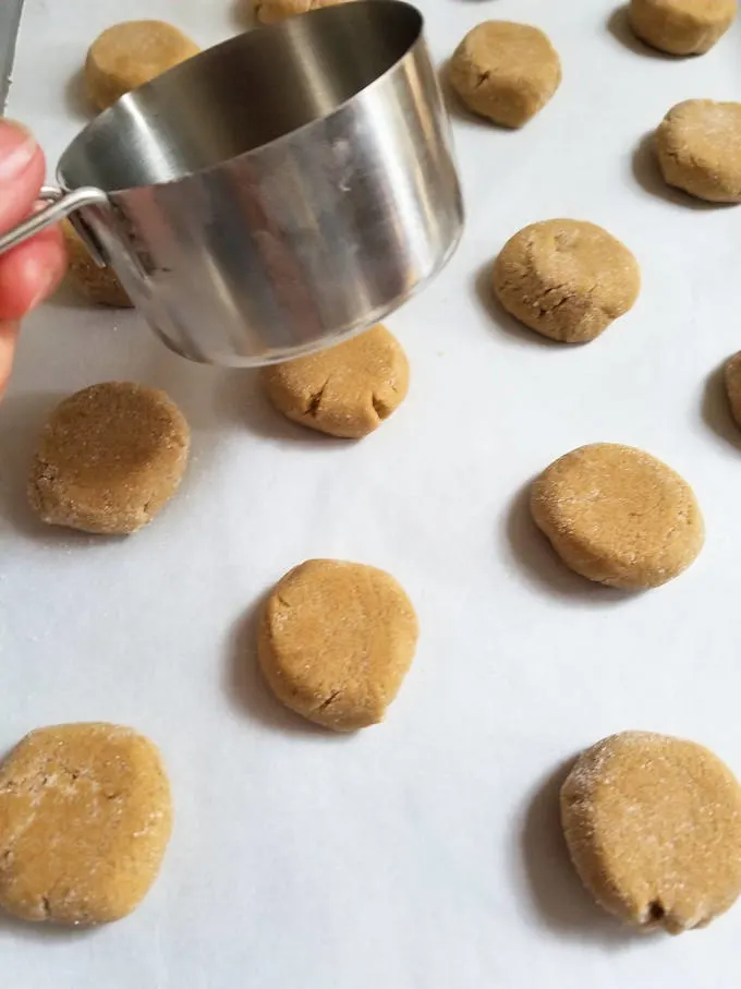a metal measuring cup, a tray with ginger cookie dough balls.