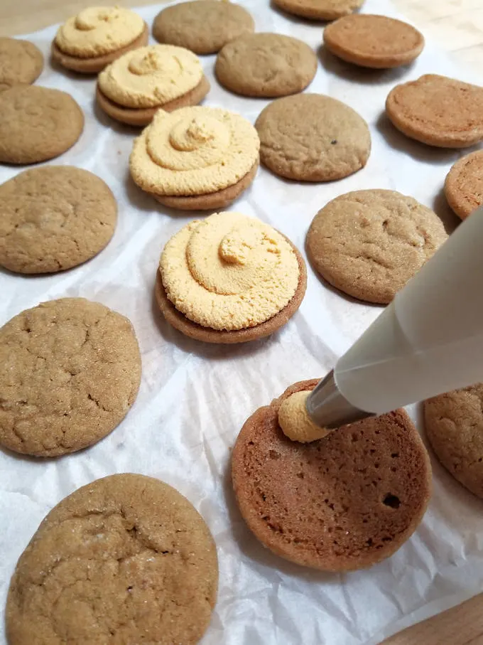 a piping bag piping ganache on cookies.