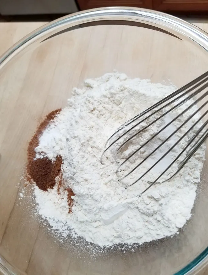 a bowl of flour and spices with a whisk.