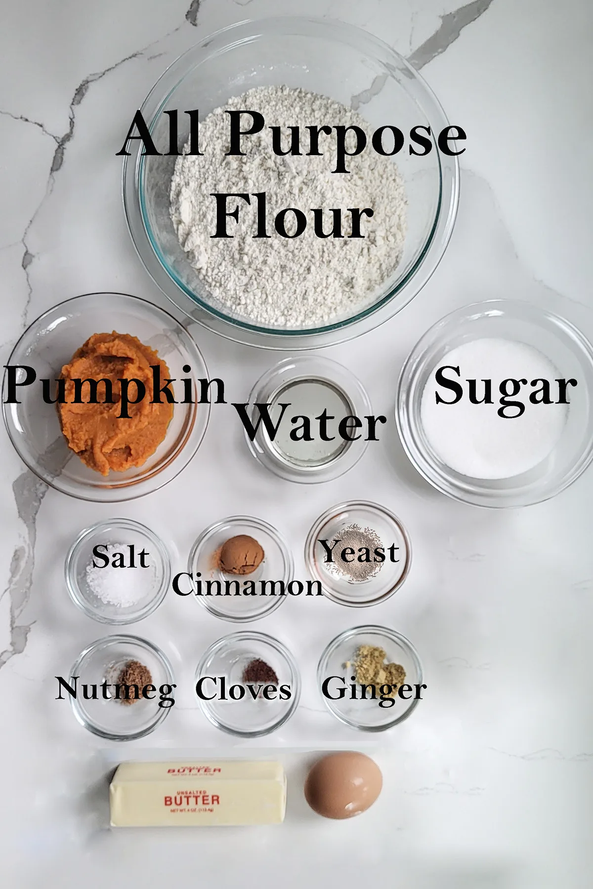 ingredients for pumpkin donuts on glass bowls on a white surface.