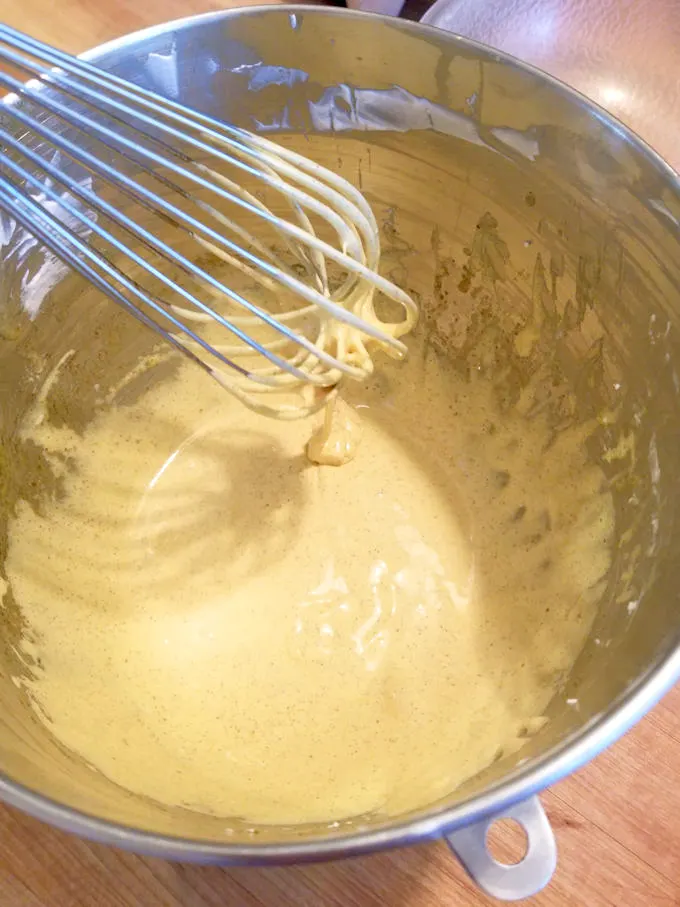 a bowl of whipped egg yolks and a whisk.