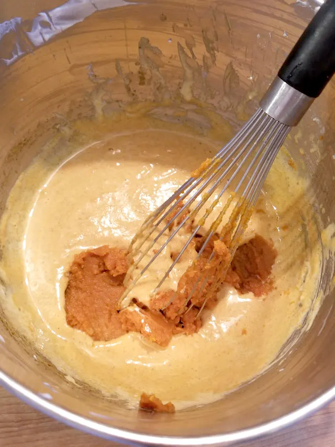 Egg yolks and pumpkin in a bowl with a whisk.