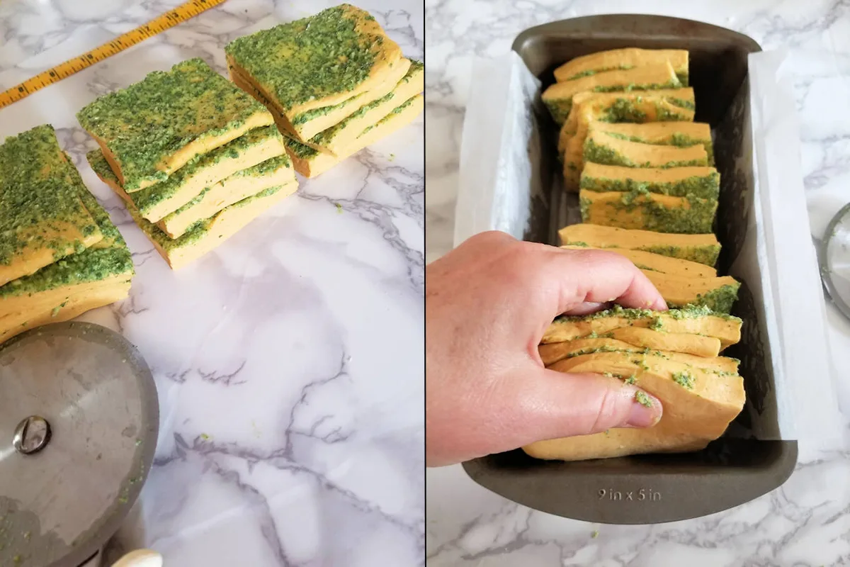 stacks of pesto coated squares of dough in a loaf pan.