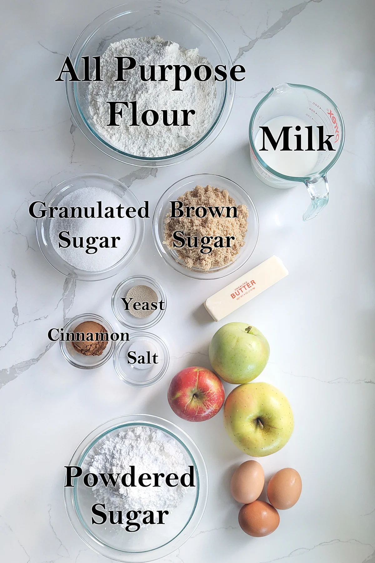 ingredients for apple cinnamon bread in glass bowls on a white surface.