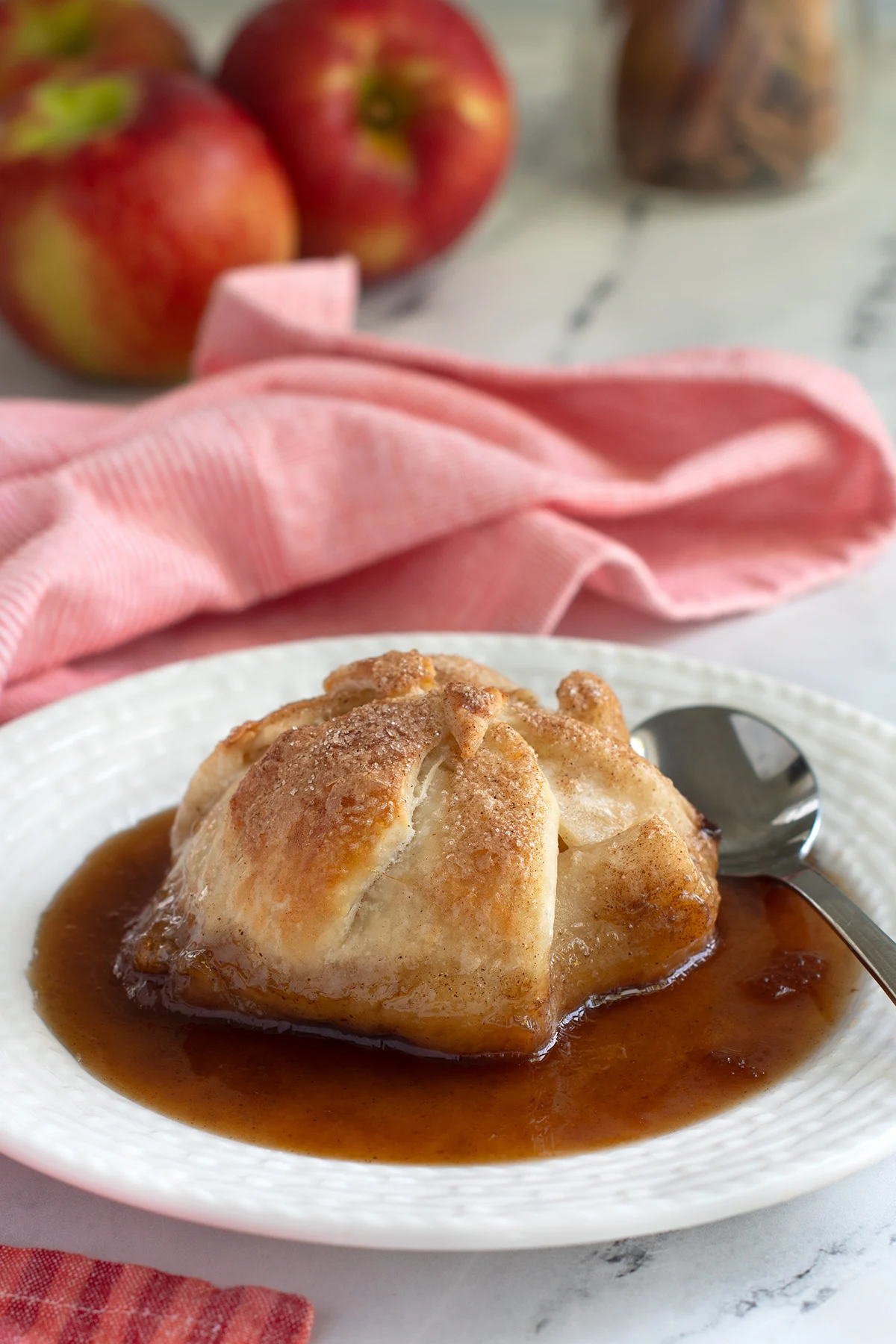 an apple dumpling on a white plate with sauce.