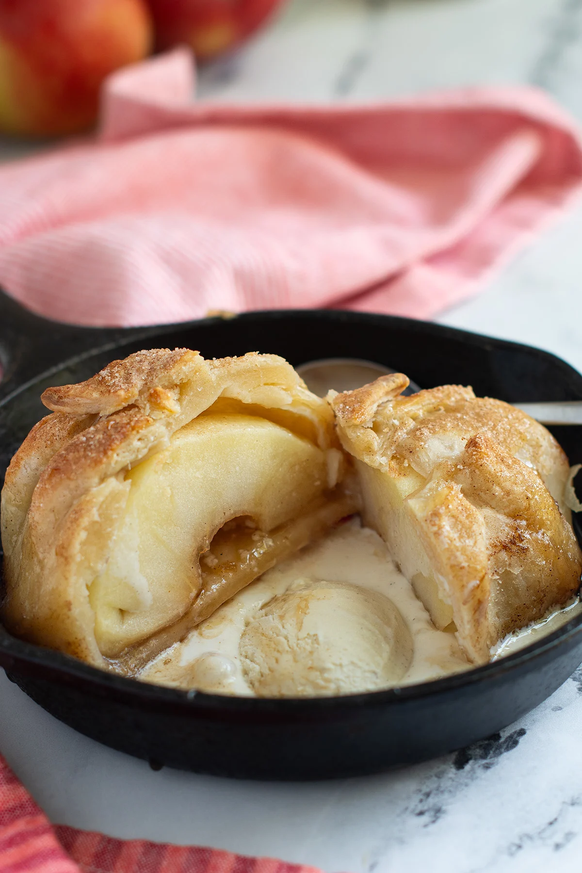 an apple dumpling in a skillet with vanilla ice cream.