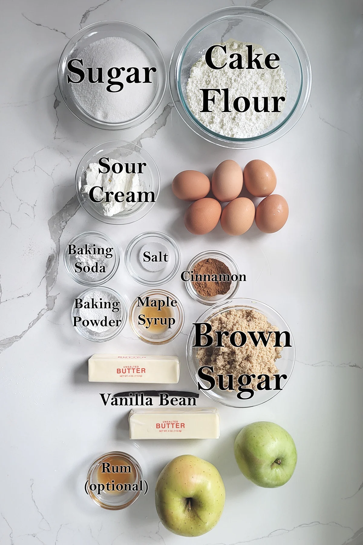 ingredients for apple maple layer cake in glass bowls on a white surface.