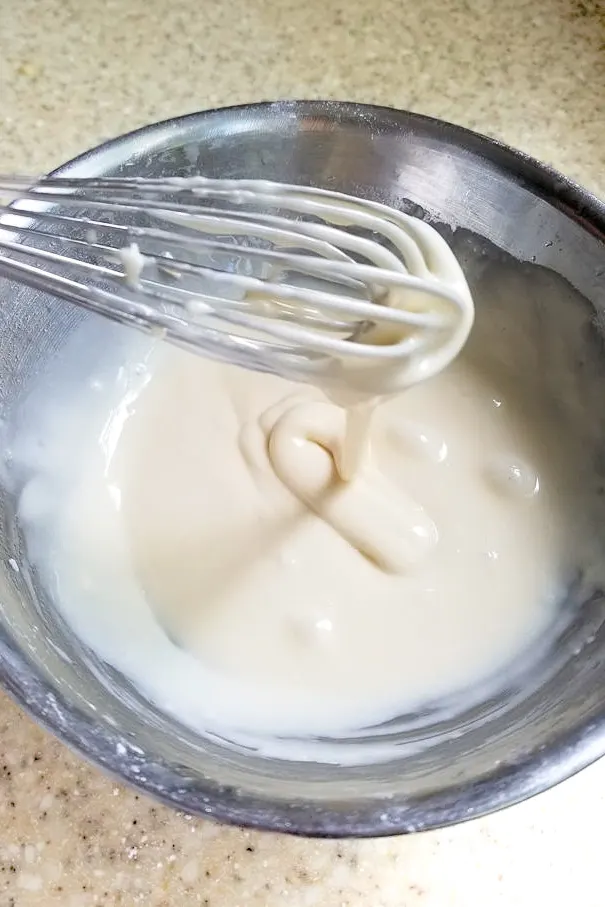 a bowl of glaze with a whisk.