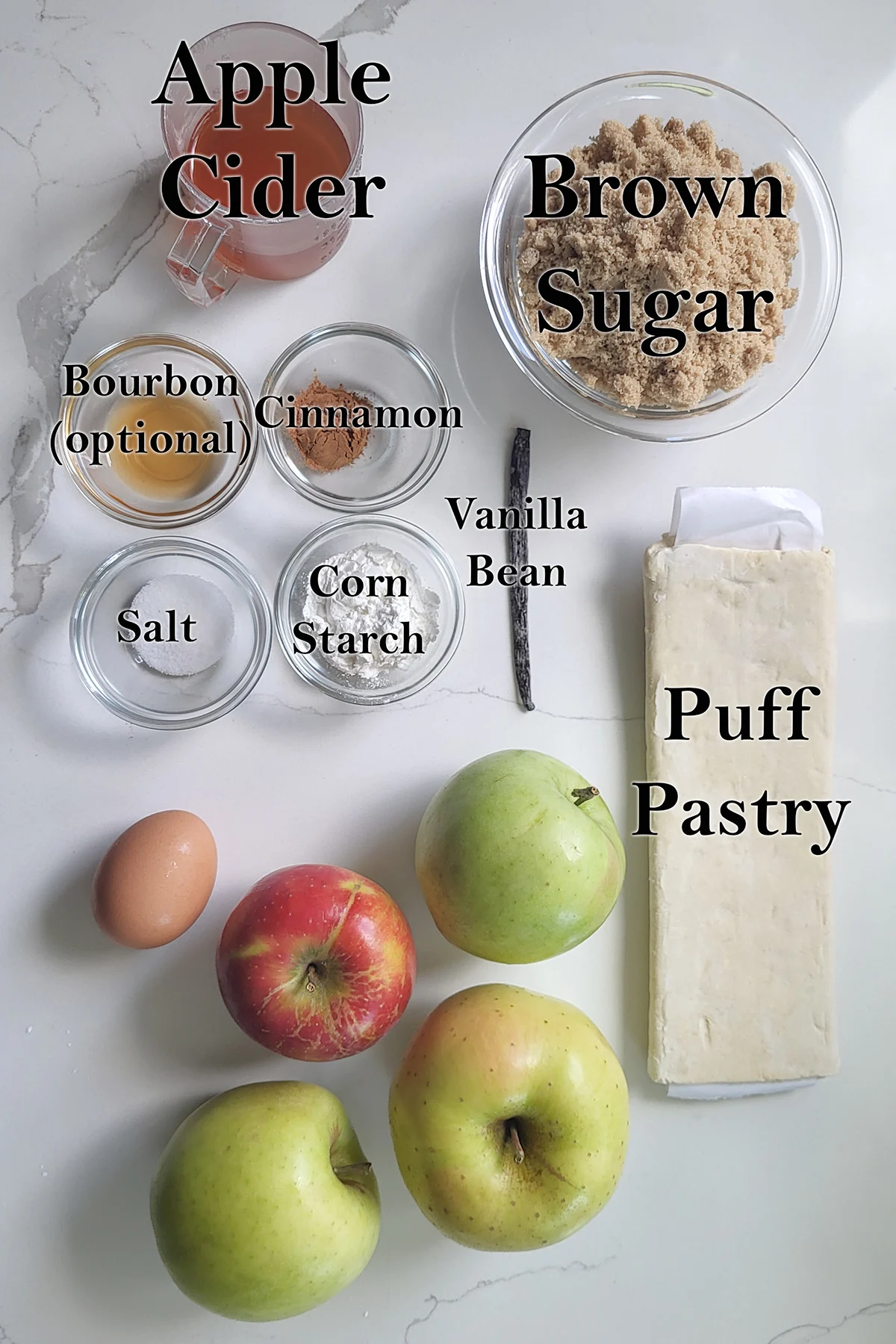 ingredients for apple bourbon pot pie in glass bowls on a white surface.