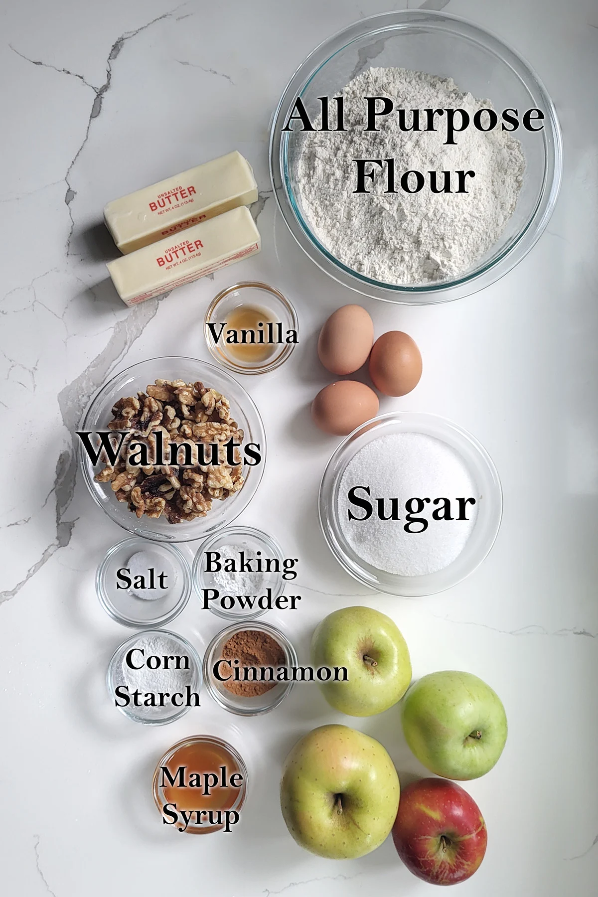 Ingredients for apple walnut linzer tart in glass bowls on a white surface.